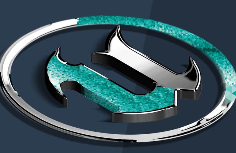 Ein stilisiertes, metallisches „Unreal“-Logo mit einem türkisfarbenen, strukturierten Design, umgeben von einem silbernen Ring auf dunklem Hintergrund.